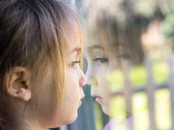 Serious girl looking through a window Serious girl looking through a window